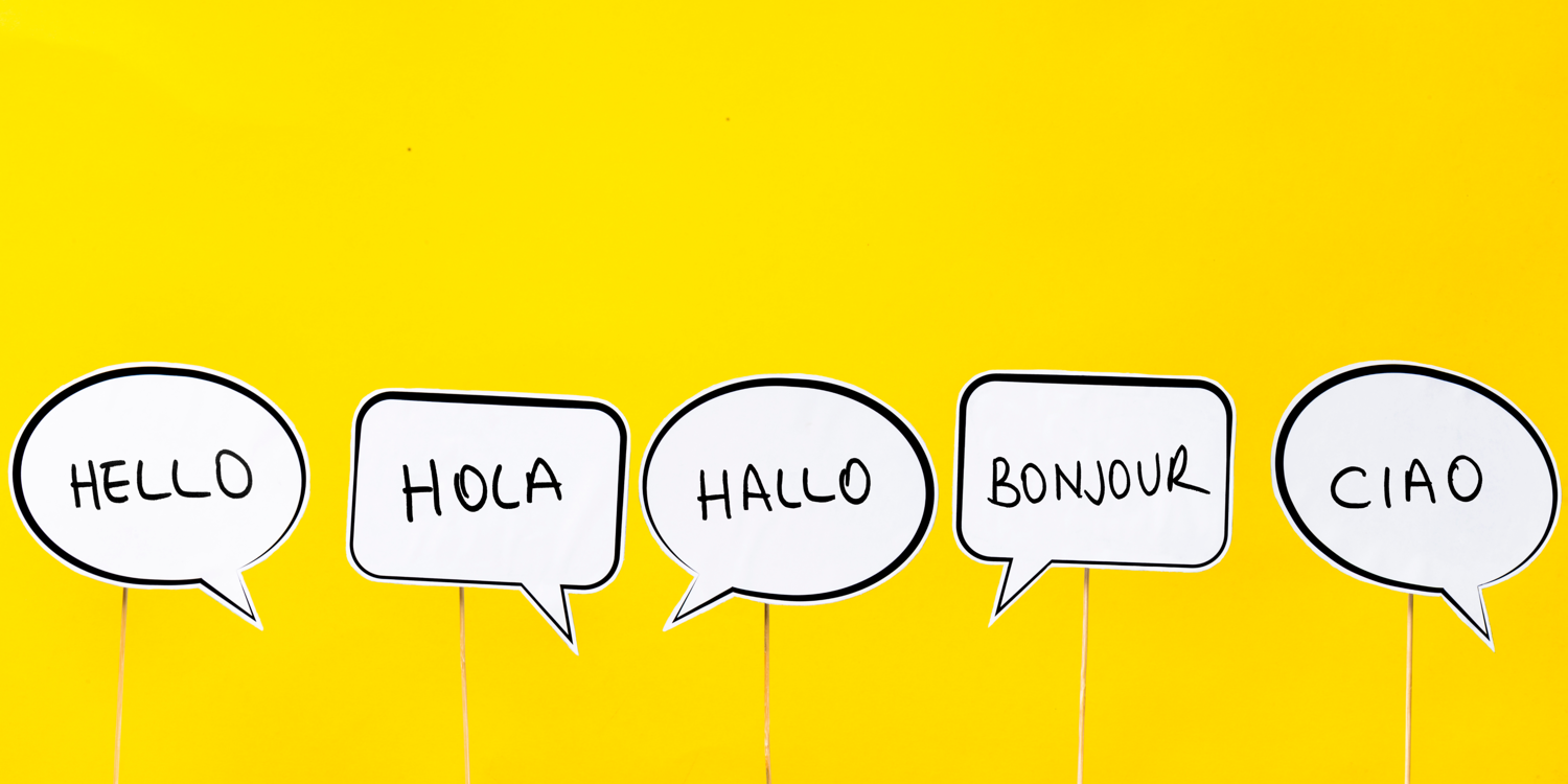 5 Sprechblasen in den auf englisch, spanisch, deutsch, französisch und italienisch 'Hallo' geschrieben steht.