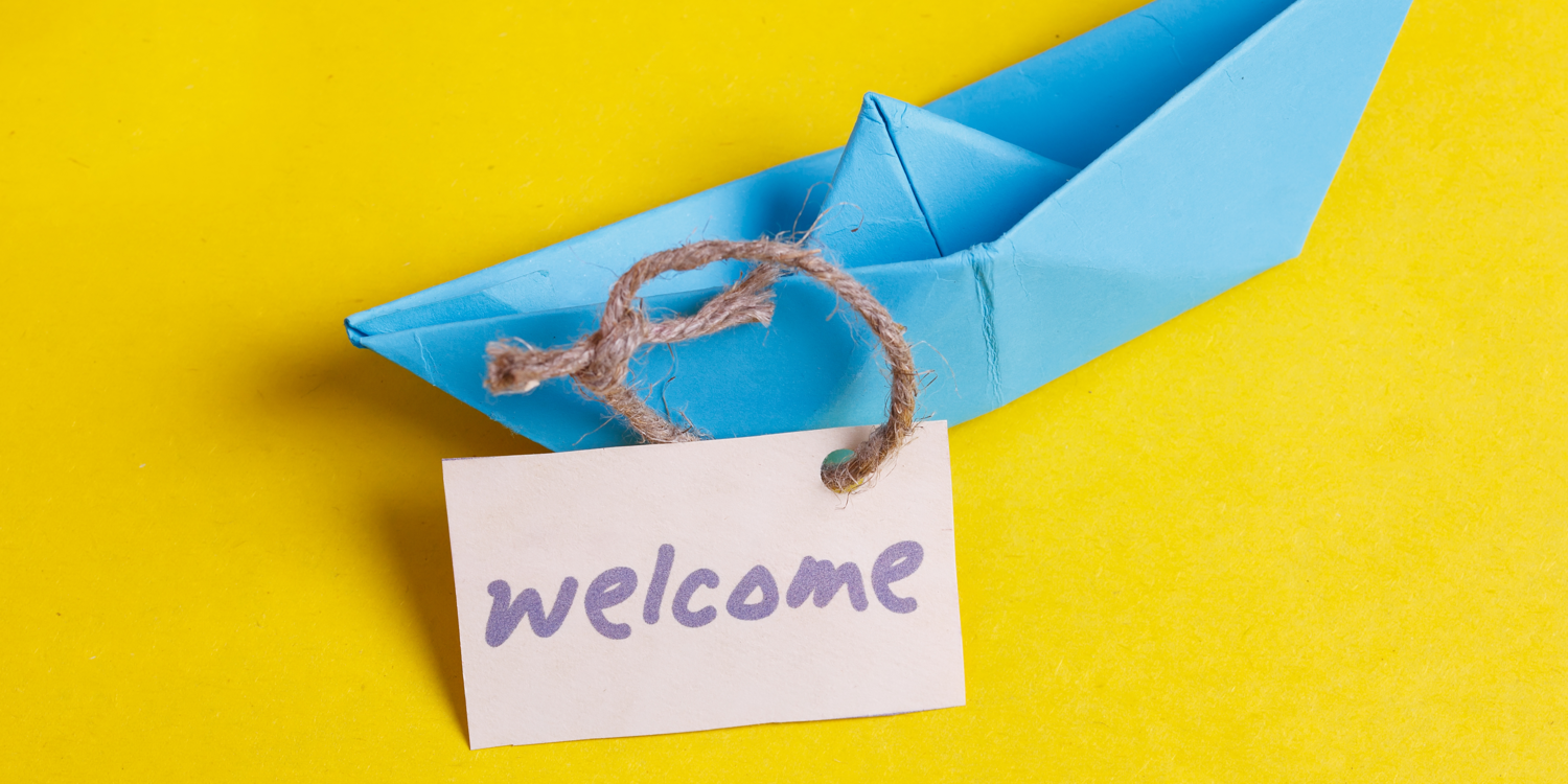auf einem Papierboot hängt ein Schild mit dem Schriftzug 'Welcome'